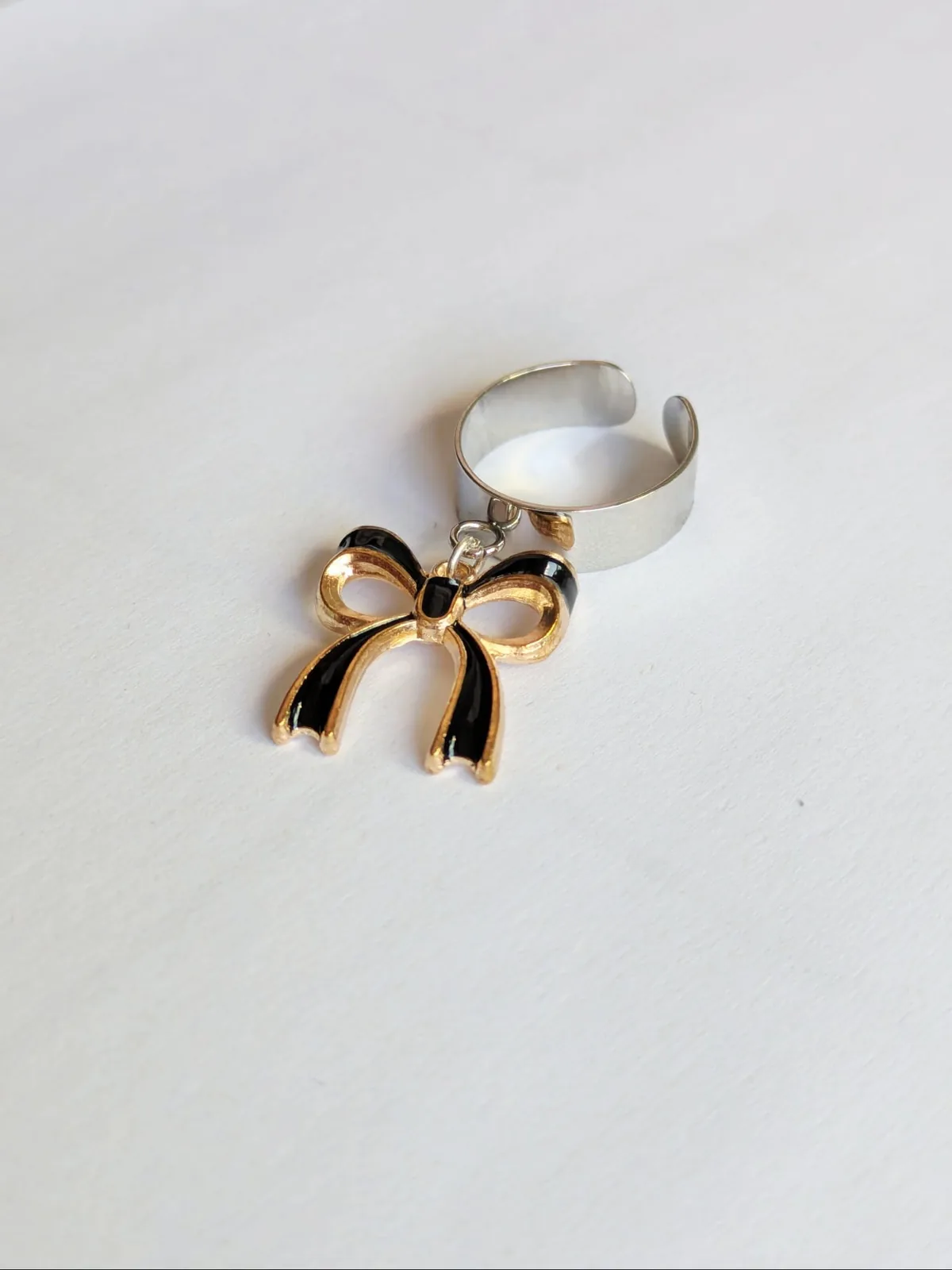 Bague ajustable à anneau ouvert argenté avec breloque nœud en émail noir et doré pendante